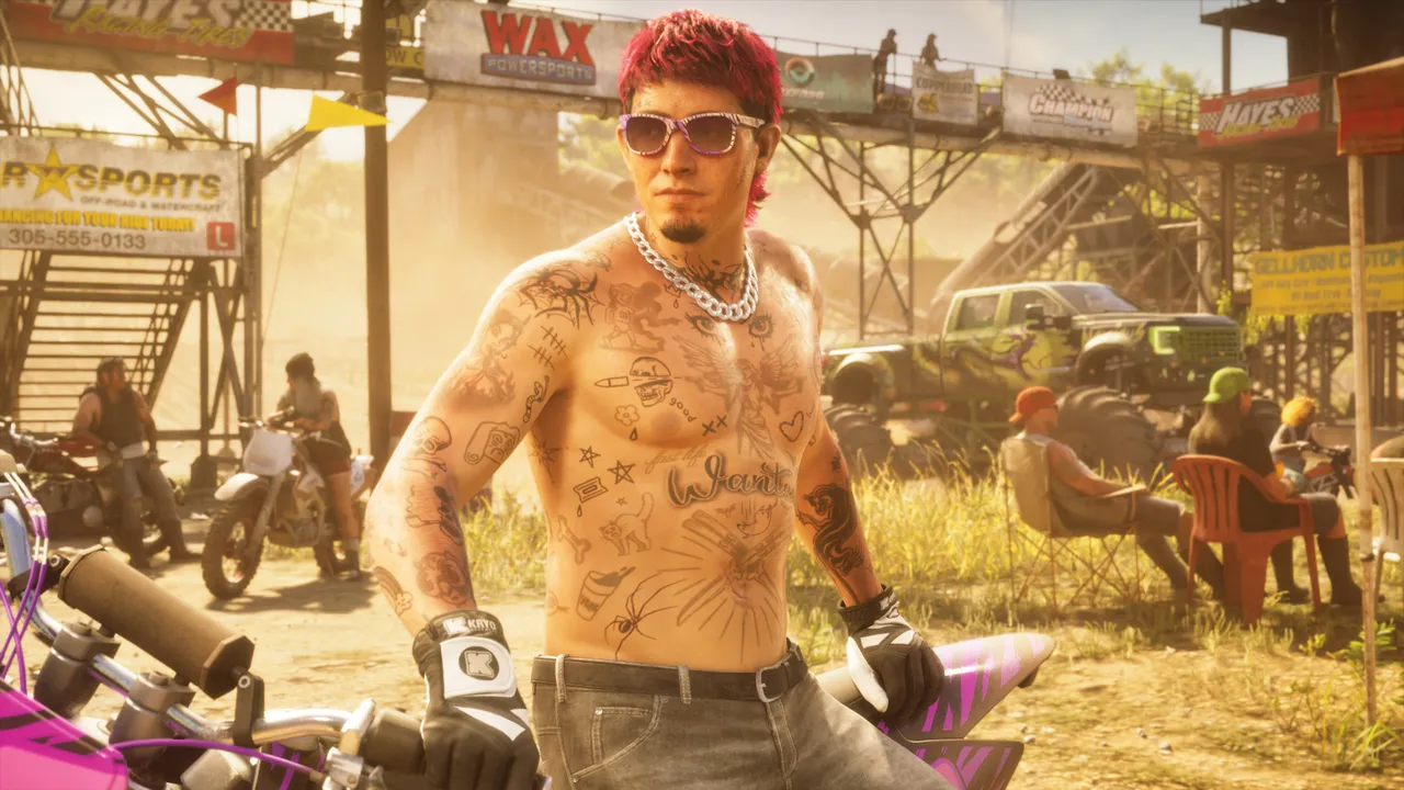 A shirtless rider with pink hair and sunglasses at a dusty dirt-bike track